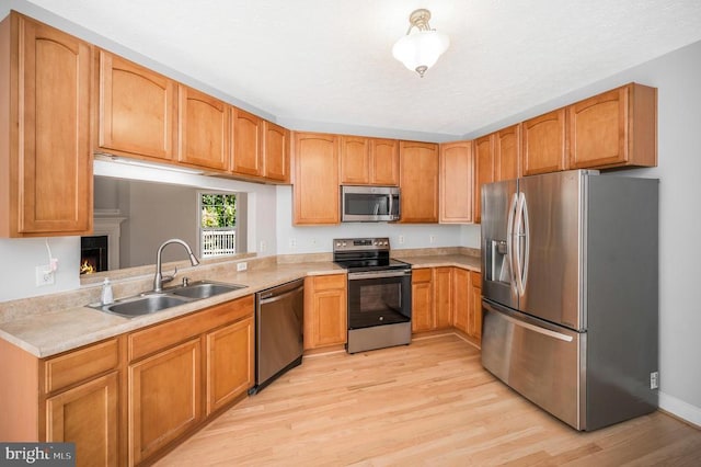 kitchen with sink, stainless steel appliances, and light hardwood / wood-style flooring