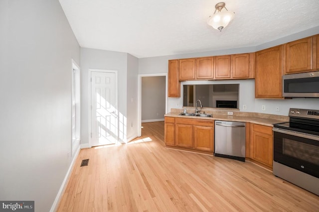 kitchen featuring stainless steel appliances, light wood-type flooring, and sink