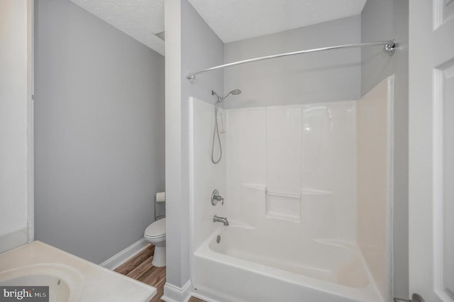 full bathroom featuring toilet, shower / tub combination, hardwood / wood-style flooring, vanity, and a textured ceiling