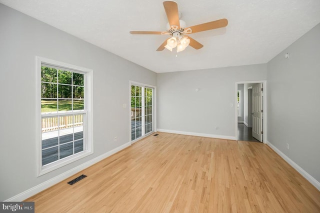 empty room featuring light hardwood / wood-style floors, a wealth of natural light, and ceiling fan