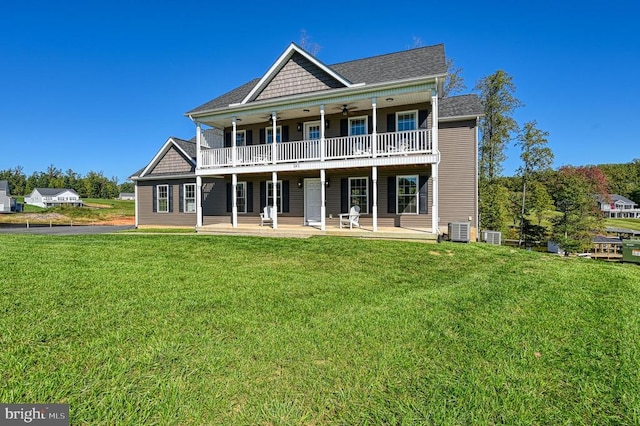 rear view of property featuring a balcony, a yard, a patio area, and central AC