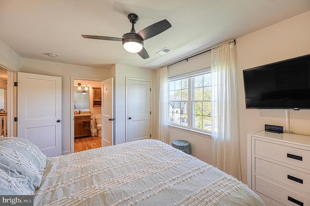 bedroom with ceiling fan, light wood-type flooring, and ensuite bath