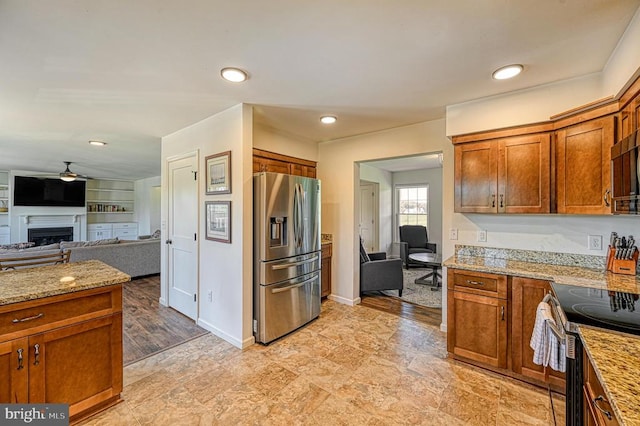 kitchen with ceiling fan, light stone countertops, stainless steel appliances, and light hardwood / wood-style floors