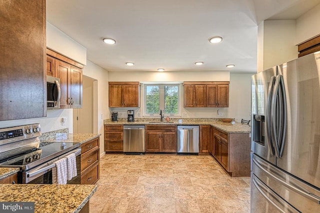 kitchen featuring stainless steel appliances, light stone countertops, and sink