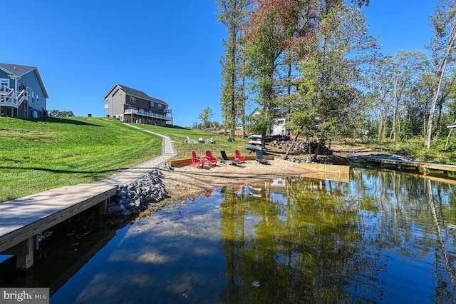 view of dock with a water view and a yard