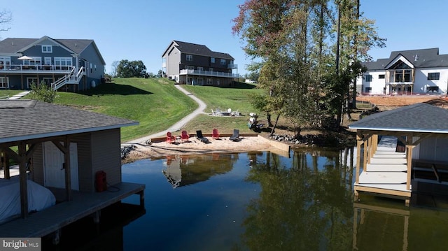 view of dock with a water view and a lawn