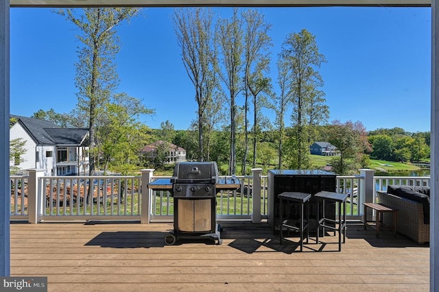 wooden terrace with a grill and a water view