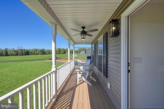 wooden terrace with a porch, ceiling fan, and a lawn