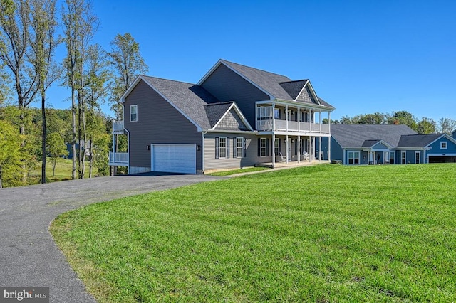 view of front of property featuring a balcony, a front yard, and a garage