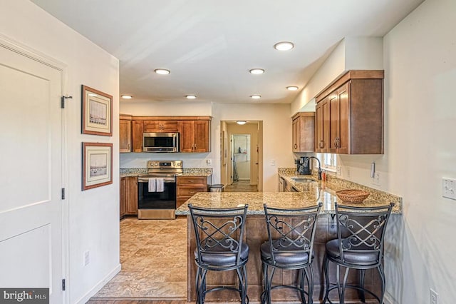 kitchen with stainless steel appliances, kitchen peninsula, a kitchen bar, and sink