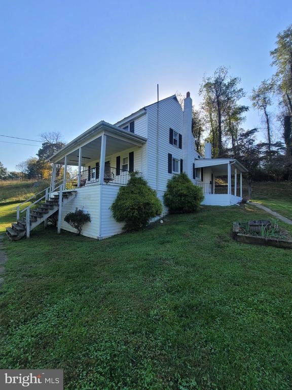 view of side of home featuring a yard and covered porch