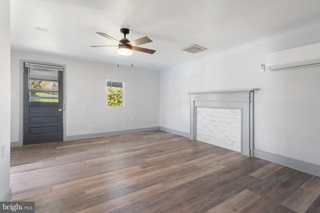 empty room with ceiling fan, a wall mounted AC, and hardwood / wood-style floors