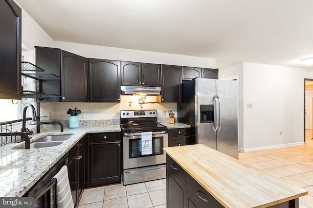 kitchen with butcher block countertops, sink, appliances with stainless steel finishes, and light tile patterned floors