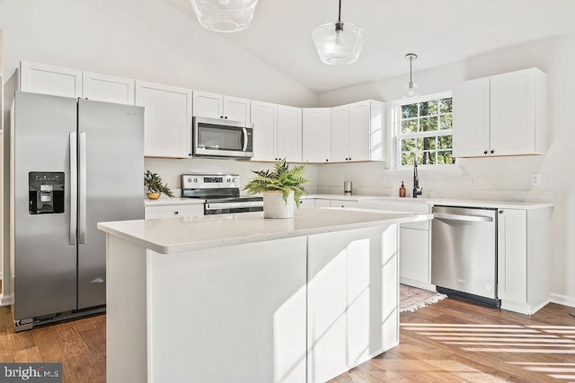 kitchen with lofted ceiling, white cabinetry, light wood-type flooring, stainless steel appliances, and decorative light fixtures