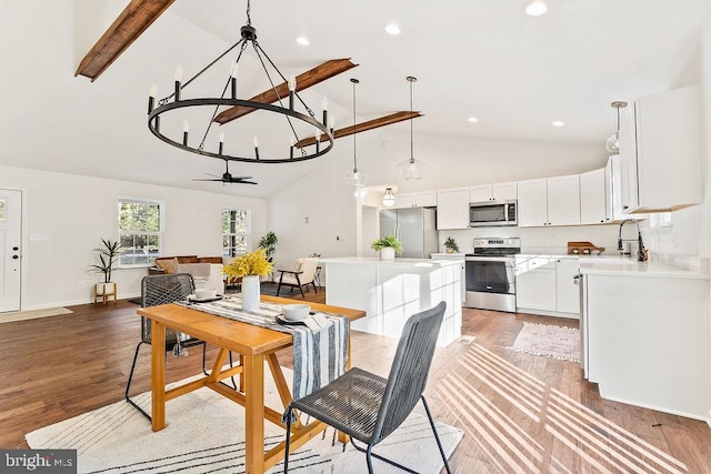 dining room featuring beamed ceiling, ceiling fan with notable chandelier, sink, hardwood / wood-style floors, and high vaulted ceiling