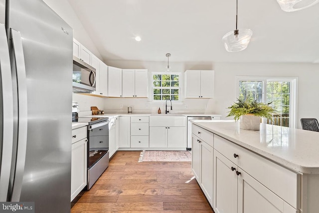 kitchen featuring appliances with stainless steel finishes, light wood-type flooring, plenty of natural light, and pendant lighting