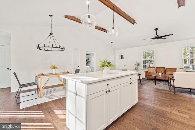 kitchen featuring a kitchen island, white cabinetry, beamed ceiling, decorative light fixtures, and dark wood-type flooring