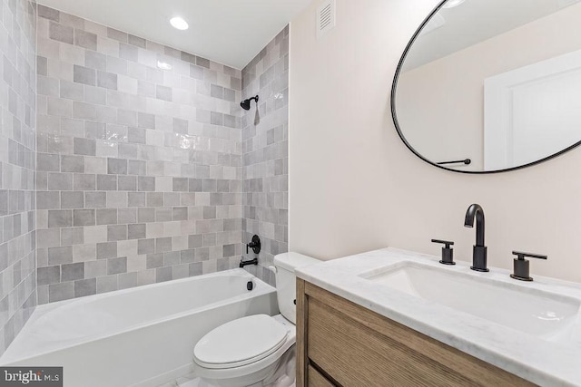 full bathroom with tiled shower / bath, vanity, and toilet