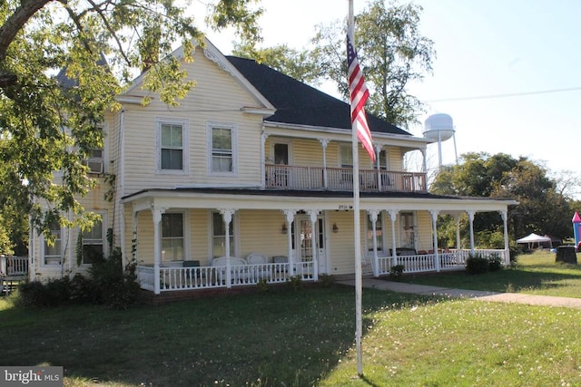 view of front of house with covered porch, a balcony, and a front lawn