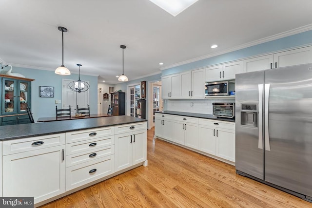 kitchen with white cabinetry, decorative light fixtures, stainless steel appliances, and light wood-type flooring