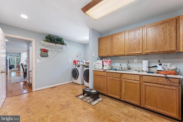 laundry area featuring washer and dryer, sink, and light wood-type flooring