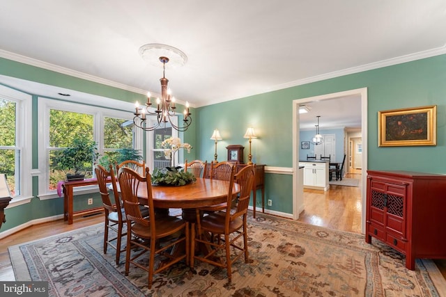 dining space with a notable chandelier, light hardwood / wood-style floors, and crown molding