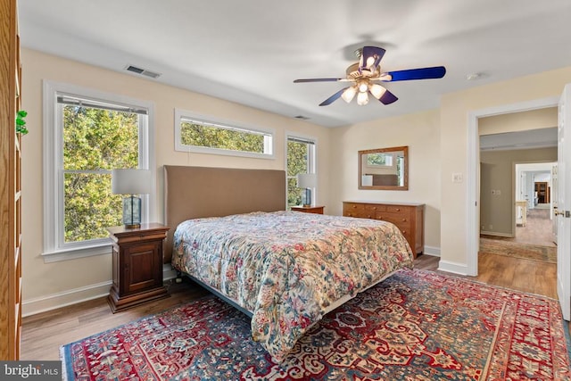 bedroom with hardwood / wood-style floors, multiple windows, and ceiling fan