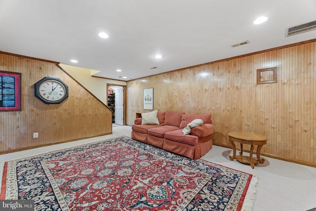 carpeted living room featuring wood walls and ornamental molding