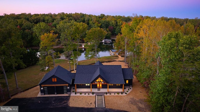 aerial view at dusk featuring a water view