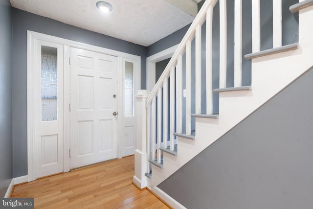 foyer entrance with a textured ceiling and light wood-type flooring