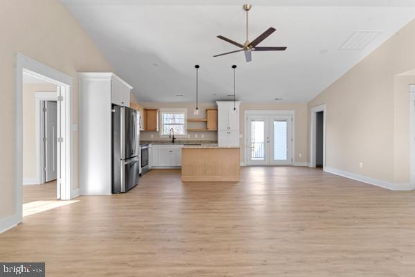 kitchen with white cabinets, range, a center island, stainless steel refrigerator, and hanging light fixtures