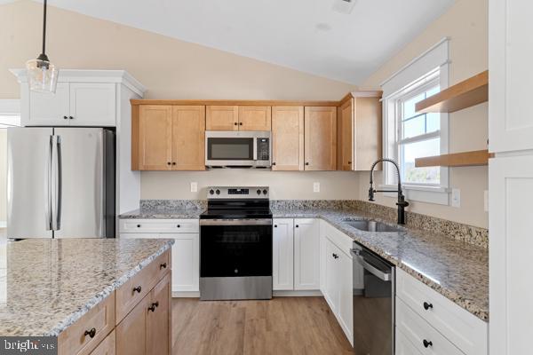 kitchen with white cabinets, sink, stainless steel appliances, and vaulted ceiling