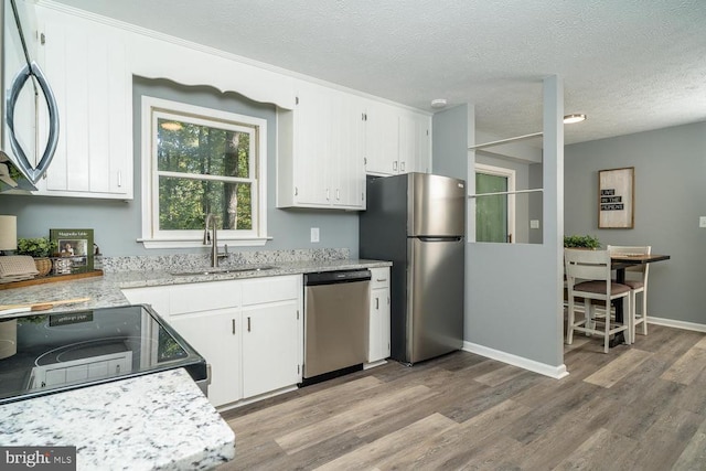 kitchen with white cabinetry, a textured ceiling, appliances with stainless steel finishes, and light hardwood / wood-style flooring