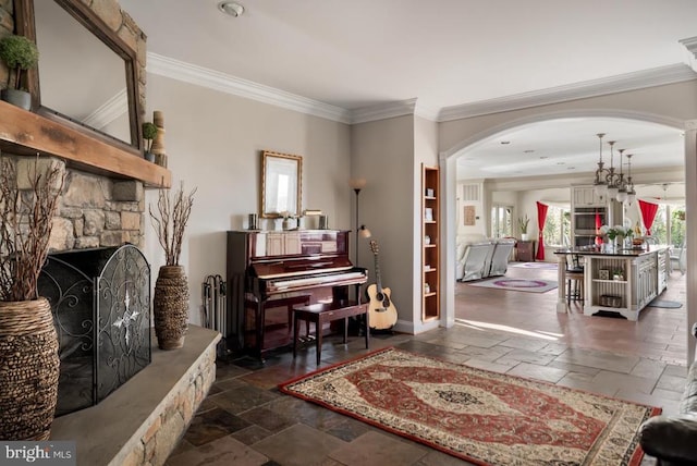 living area with a stone fireplace and ornamental molding