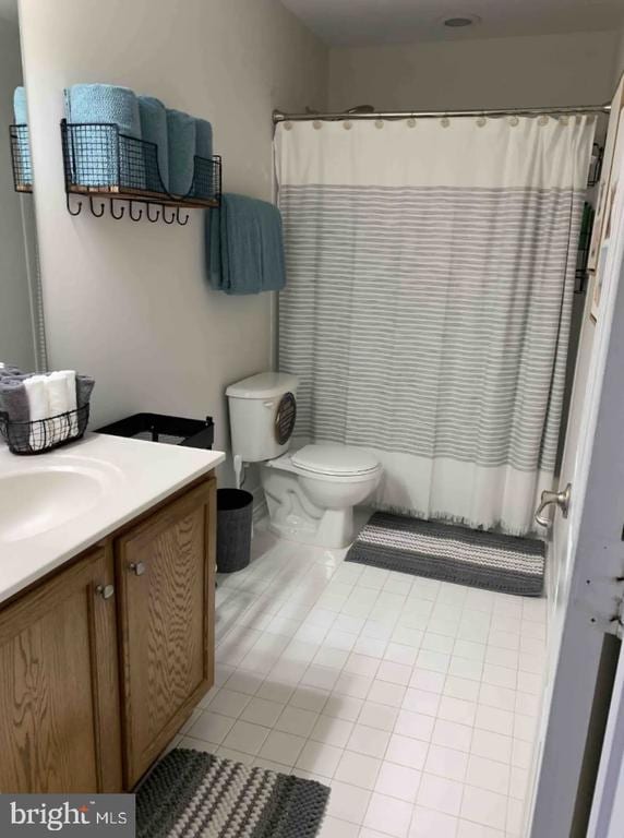 bathroom with vanity, curtained shower, toilet, and tile patterned floors