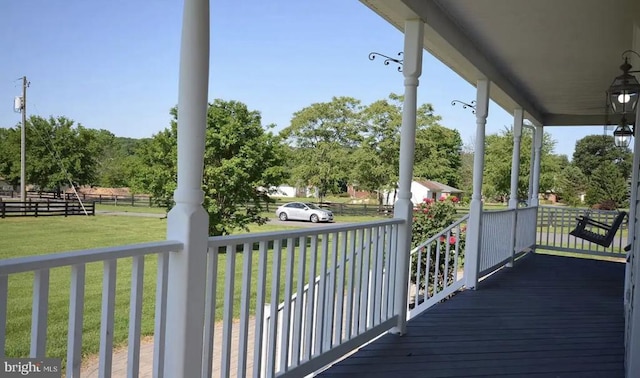 wooden deck featuring covered porch and a lawn