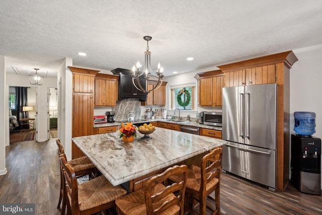 kitchen featuring a kitchen island, dark hardwood / wood-style floors, sink, decorative light fixtures, and stainless steel appliances