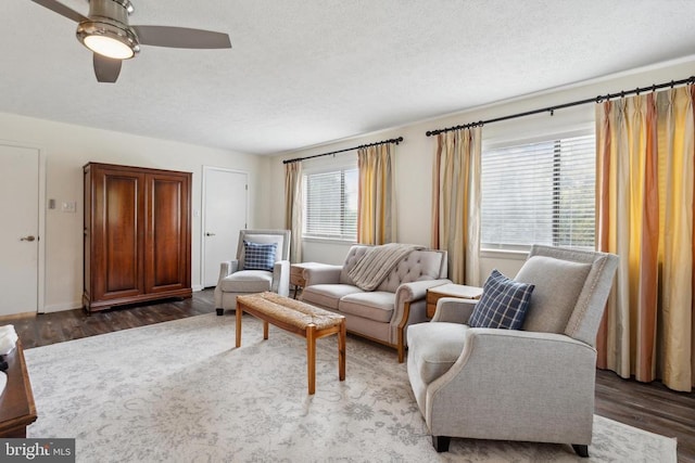 living room featuring ceiling fan, a textured ceiling, and dark hardwood / wood-style flooring