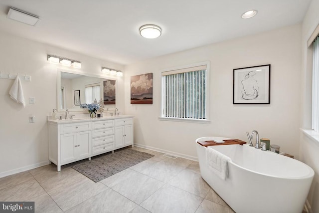 bathroom featuring vanity, a tub, and a healthy amount of sunlight