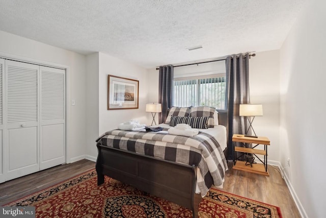 bedroom with a closet, wood-type flooring, and a textured ceiling