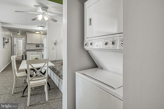 clothes washing area featuring stacked washer and dryer, carpet flooring, and ceiling fan