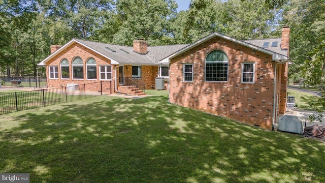 back of house with central air condition unit and a lawn