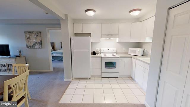 kitchen with white cabinets, light tile patterned floors, and white appliances