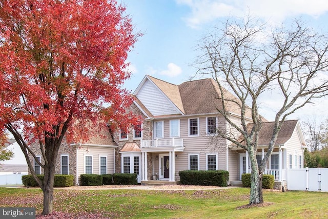 colonial inspired home featuring a balcony and a front lawn