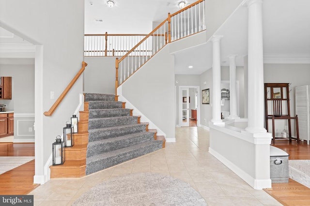 interior space featuring ornamental molding, hardwood / wood-style floors, ornate columns, and a towering ceiling