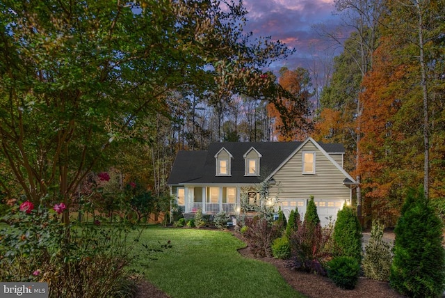 cape cod home featuring a yard, a porch, and a garage