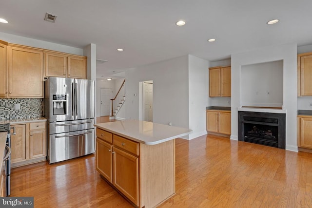 kitchen featuring decorative backsplash, a center island, light wood-type flooring, and stainless steel refrigerator with ice dispenser