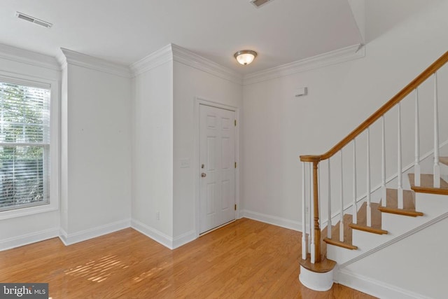 foyer entrance with ornamental molding and hardwood / wood-style flooring