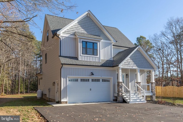 view of front of home featuring an attached garage, fence, board and batten siding, and roof with shingles