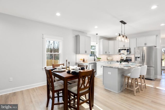 kitchen featuring decorative backsplash, stainless steel appliances, a center island, light hardwood / wood-style floors, and hanging light fixtures